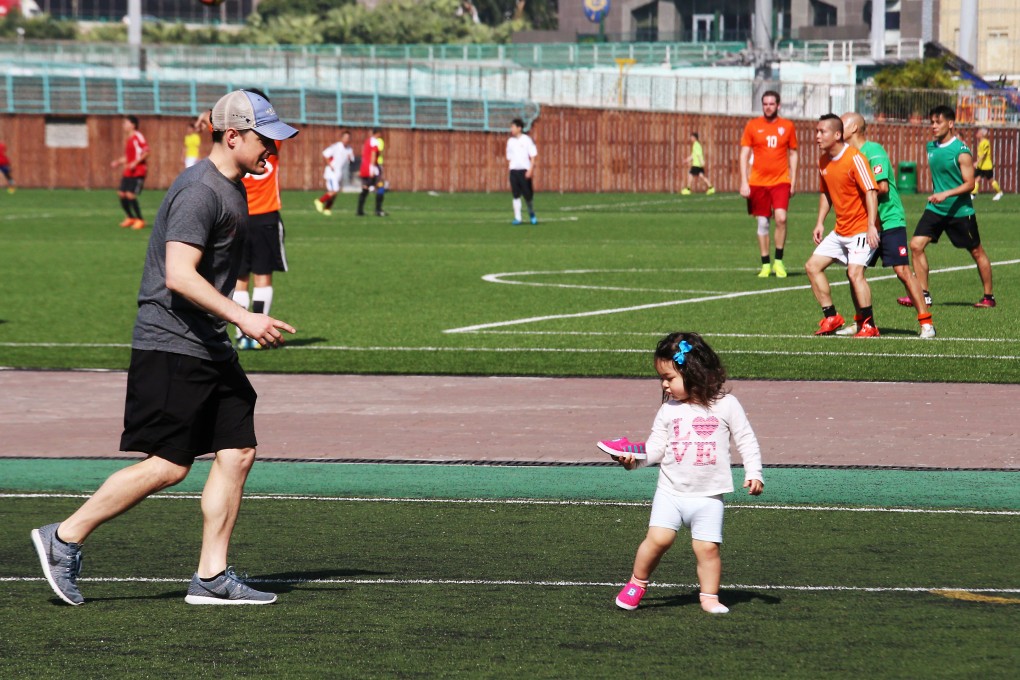 A child examines her shoe as footballers enjoy a game at Happy Valley Recreation Ground in 2017. The ground still attracts people of a variety of nationalities. Photo: David Wong