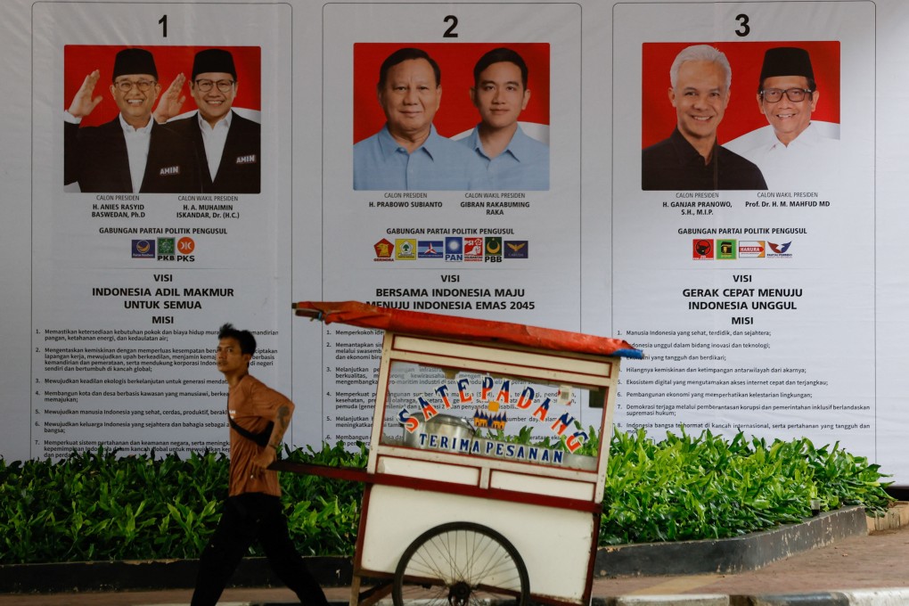 A street vendor pulls his cart past a banner showing presidential candidates contesting the upcoming general election in Jakarta, Indonesia, on Saturday. Photo: Reuters