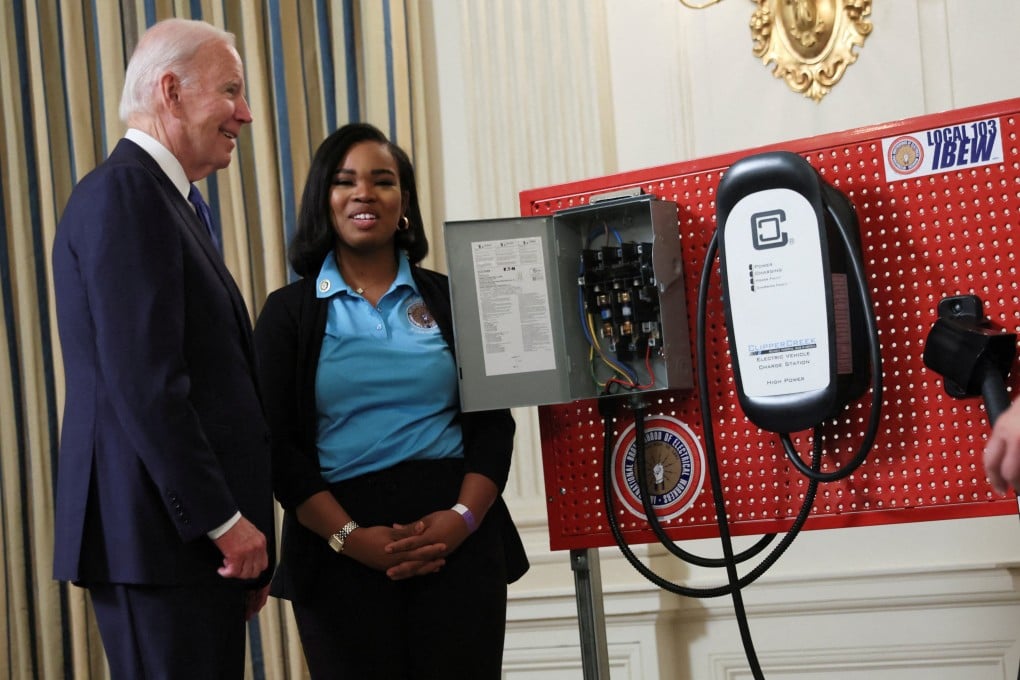 US President Joe Biden speaks with an unidentified representative of the International Brotherhood of Electrical Workers as he looks at an EV charging station display in November 2022. Photo: Reuters