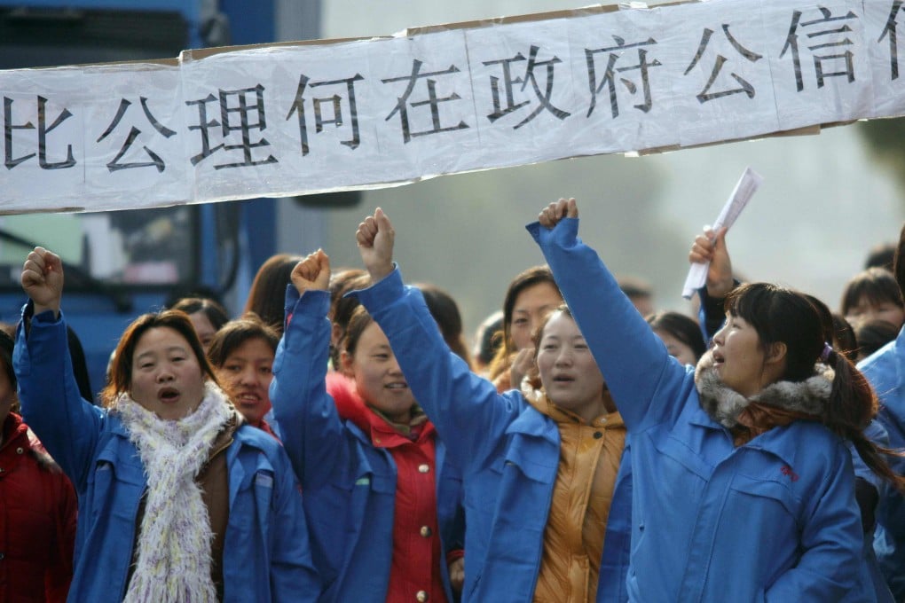 Striking workers hold a banner asking, among other things, how they can trust the government, as they protest against planned lay-offs at a factory in Shanghai on December 2, 2011. Photo: Reuters