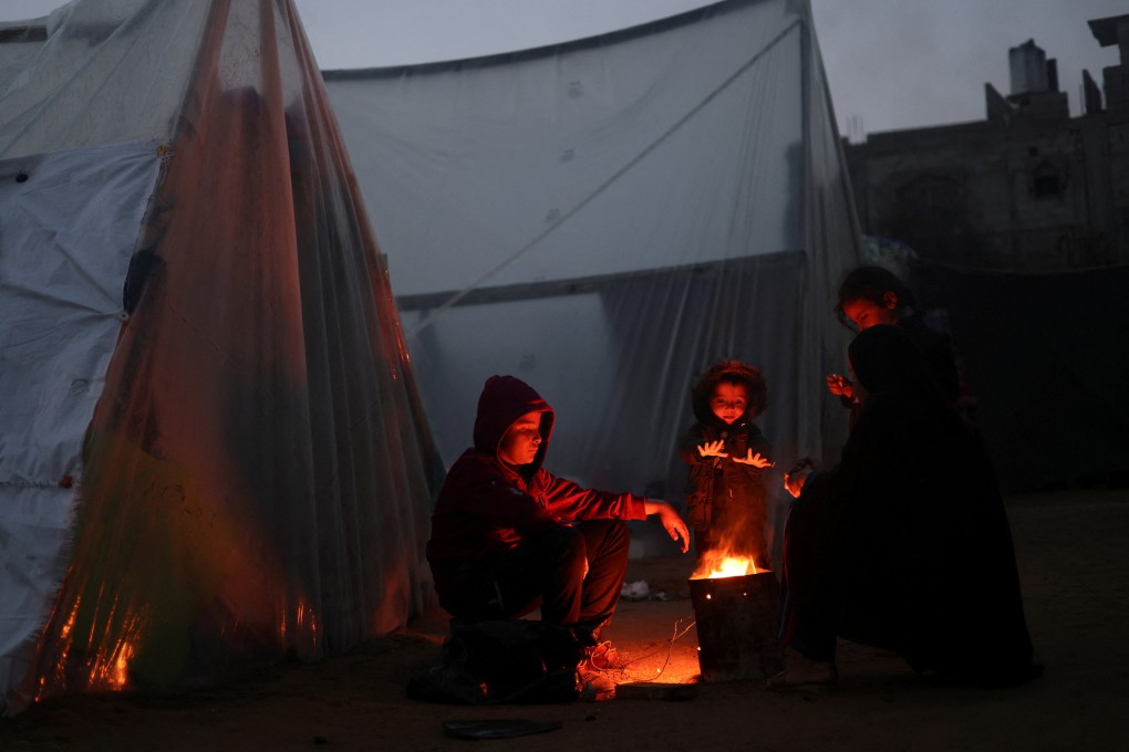 Palestinian refugees, who fled their houses due to Israeli strikes, warm themselves by a fire at a tent camp in Rafah in the southern Gaza Strip on Friday. Photo: Reuters