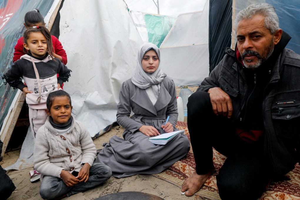 Aseel Abu Haddaf (middle), a Palestinian medical student who fled her house in Khan Younis with her family, sits next to her father at a tent camp where they shelter in Rafah in the southern Gaza Strip. Photo: Reuters