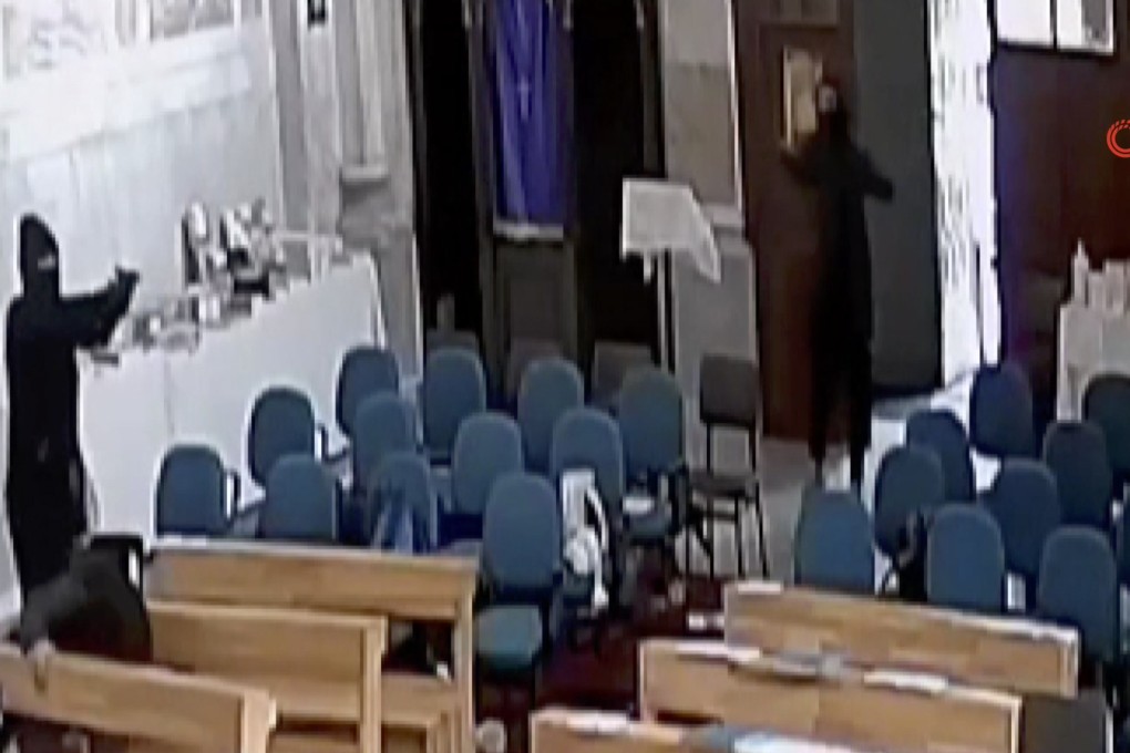 A screenshoot from video footage taken from a CCTV camera shows two masked men holding guns inside Santa Maria church in Istanbul, Turkey on Sunday. Photo: IHA via AP