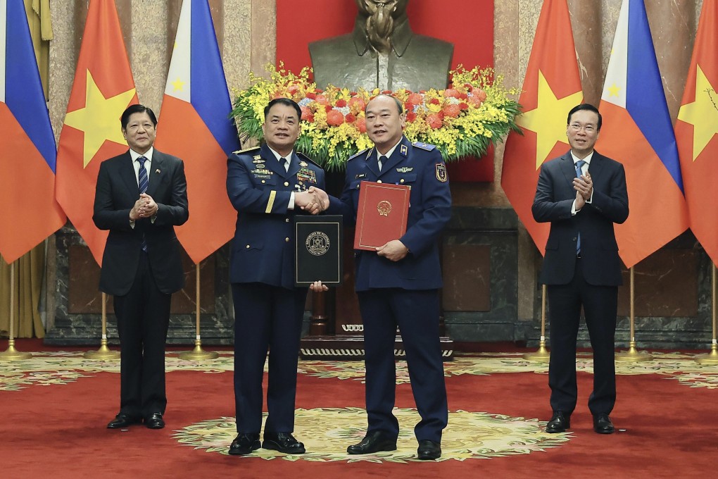 Philippine President Ferdinand Marcos Jnr (left) and Vietnamese President Vo Van Thuong (right) look on as the Philippine Coastguard Commander Admiral Ronnie Gil Gavan and Vietnamese Coastguard Commander Le Quang Dao exchange signed documents in Hanoi on Tuesday. Photo: VNA via AP