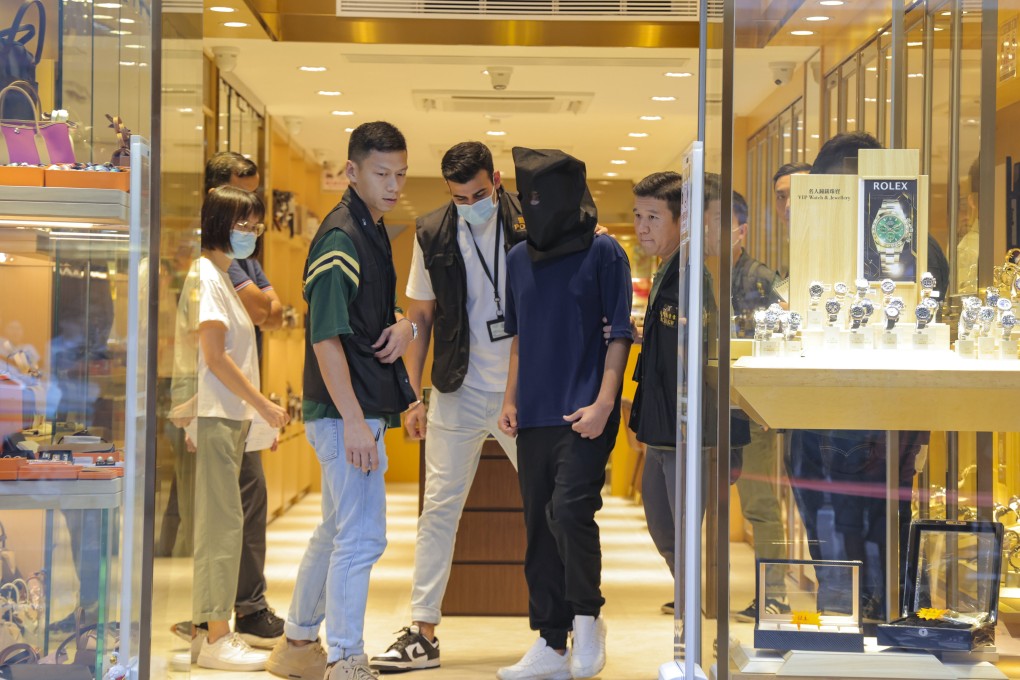 Police officers escort a suspect during a crime scene case reconstruction at a Tsim Sha Tsui watch store in September last year. Photo: Jelly Tse