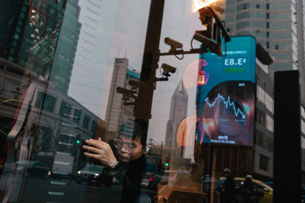 A man works in a shop while a large screen showing the latest stock exchange and economic data is seen reflected on the window in Shanghai on January 29. Photo: EPA-EFE