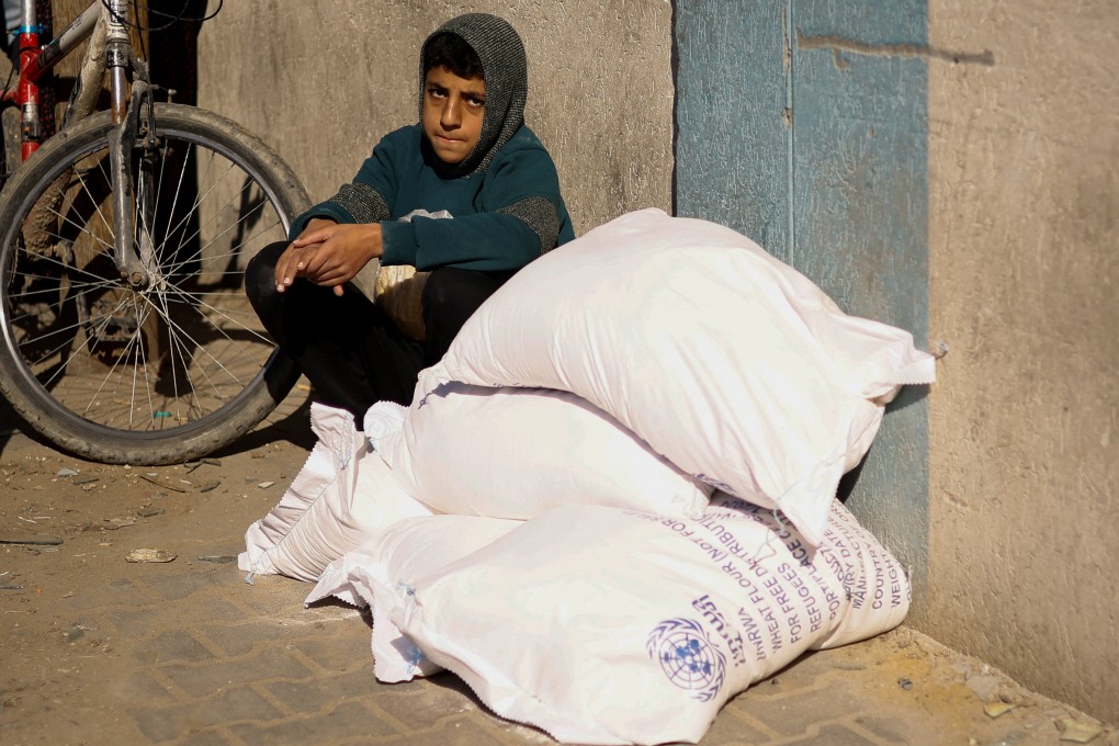 A Palestinian youth sits next to bags of flour distributed by the United Nations Relief and Works Agency (UNRWA), amid the ongoing conflict between Israel and Palestinian Islamist group Hamas. Photo: Reuters