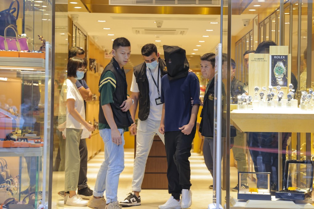 Police officers escort a suspect during a crime scene case reconstruction at a Tsim Sha Tsui watch store in September last year. Photo: Jelly Tse