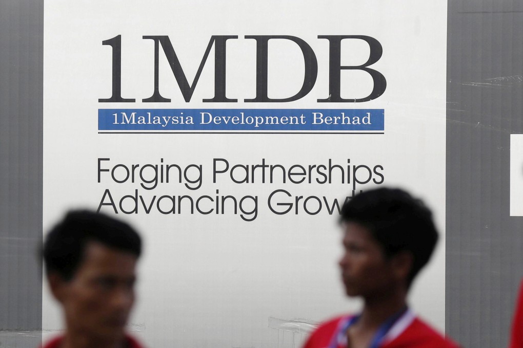 Men walk past a 1MDB billboard in Kuala Lumpur on March 1, 2015. Malaysian authorities say they have recouped about US$5 million in assets related to the 1MDB scandal. Photo: Reuters