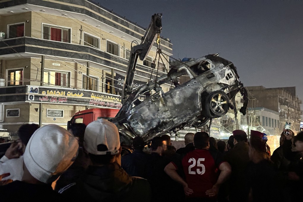 People gather as a destroyed vehicle is loaded onto a truck after what security sources said was a deadly drone strike in Baghdad, Iraq on Wednesday. Photo: Reuters