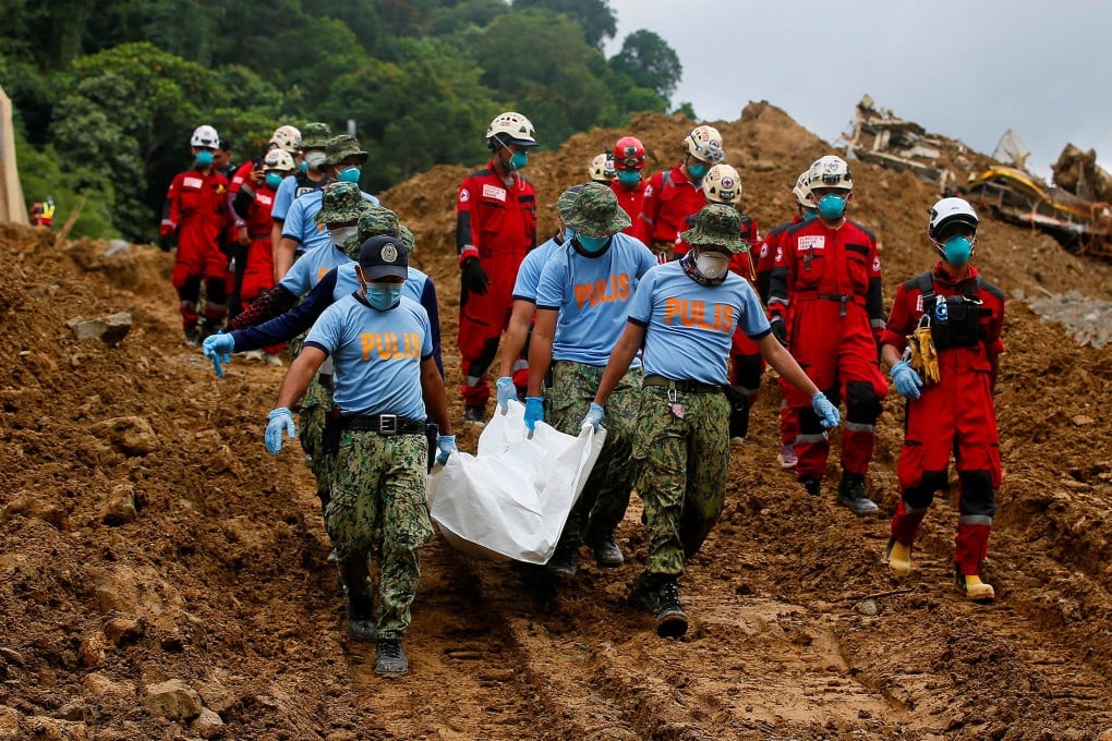 Police officers in the Philippines carry a body bag as the search for landslide survivors continues. Photo: Reuters