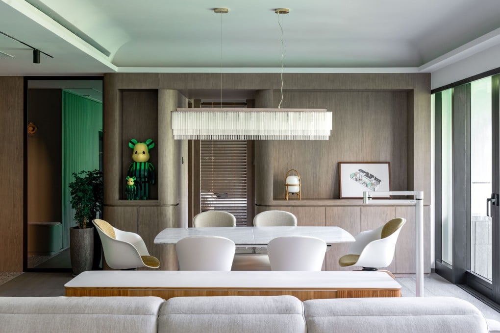 The living and dining area of a Hong Kong apartment renovated with art deco touches to make the most of its views of verdant hillsides nearby. The use of wood and stone, and green accents, ties inside and outside together. Photo: Eugene Chan