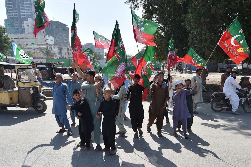 Supporters of convicted former Prime Minister Imran Khan’s Pakistan Tehrik-e-Insaf (PTI) party hold party flags during general elections in Karachi, Pakistan: Photo: EPA-EFE