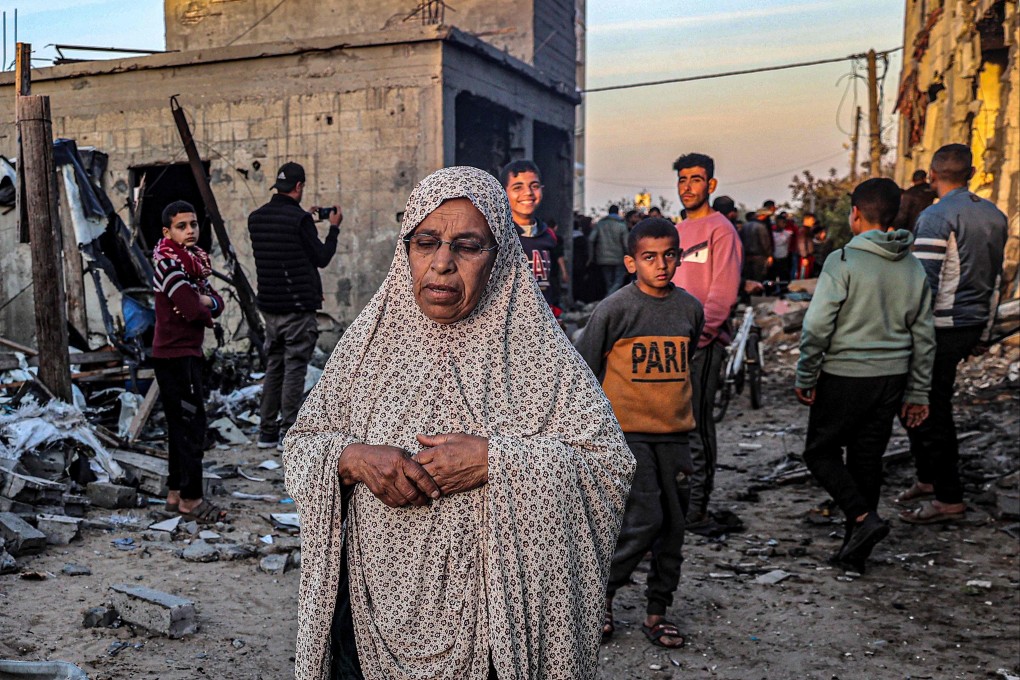 An elderly woman walks past buildings heavily damaged by Israeli bombardment in Rafah, southern Gaza on Sunday. Photo: AFP