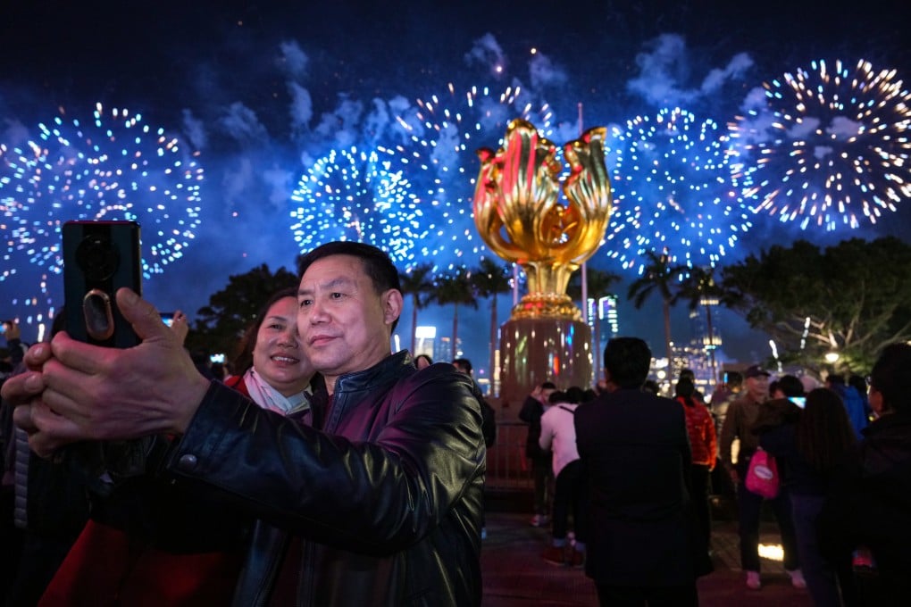 Revellers take in the fireworks display from Golden Bauhinia Square in Wan Chai. Photo: Eugene Lee