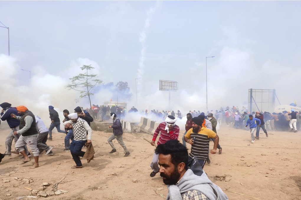 Farmers run for cover after police fired tear gas to disperse protesting farmers who were marching to New Delhi near the Punjab-Haryana border. Photo: AP