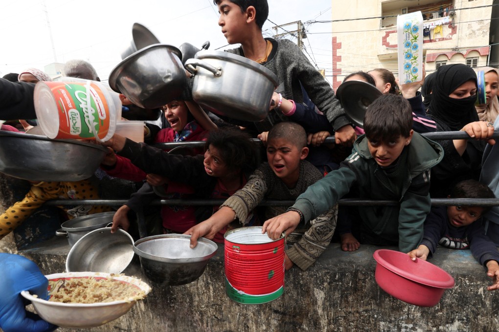 Palestinian children wait to receive food cooked by a charity kitchen in Rafah, in the southern Gaza Strip, on Tuesday. Photo: Reuters