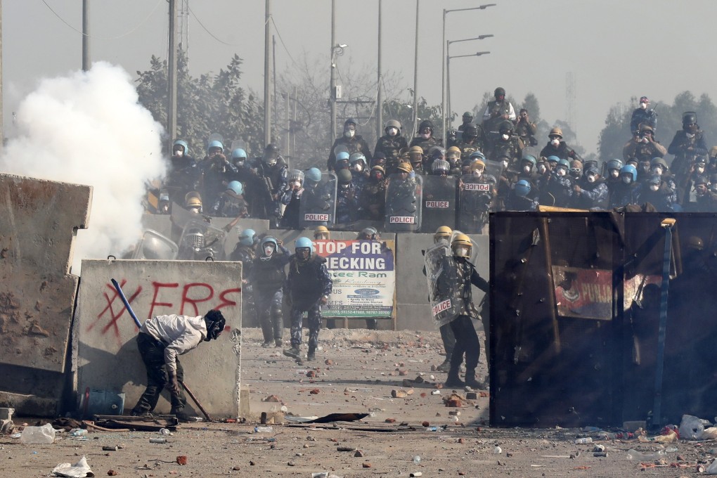Protesting farmers take shelter during clashes with Indian police, as police try to prevent them from moving towards Delhi. Photo: EPA-EFE