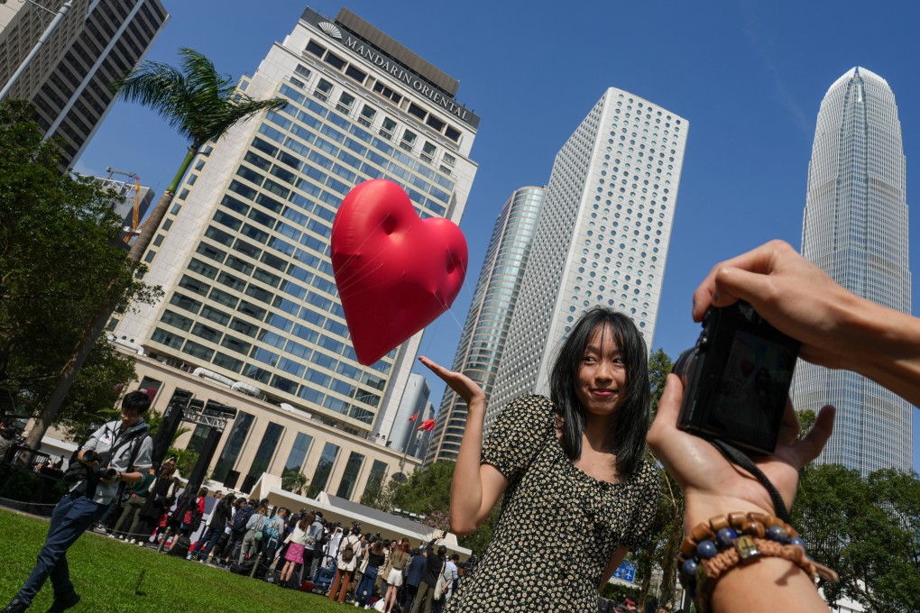 Visitors pose for pictures with the “Chubby Hearts” art installation at Statue Square Gardens in Central. Photo: Sam Tsang