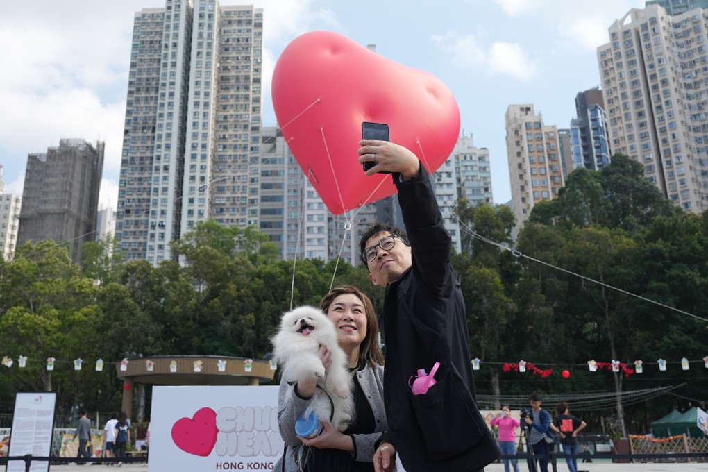 A couple pose with their dog in front of a  “Chubby Hearts” installation by fashion designer Anya Hindmarch in Kennedy Town on February 14. Photo: Eugene Lee