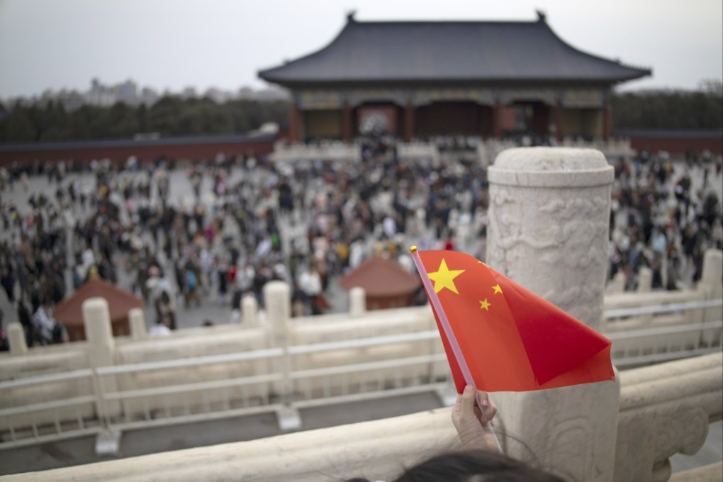 A girl holds a Chinese flag as visitors are seen in the background at the Temple of Heaven during celebrations of Chinese New Year in Beijing, February 14, 2024. Photo: EPA-EFE