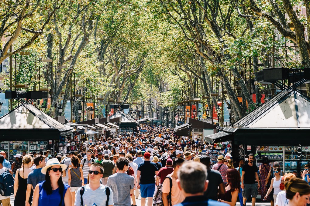 Tourists on La Rambla, in Barcelona, Spain. The city is dealing with rising temperatures and an excess of visitors, using US$108 million raised by tourist tax to install solar-powered air-conditioners in its schools. Other tourist-heavy cities such as Paris and Venice are considering similar long-term green ideas. Photo: Getty Images