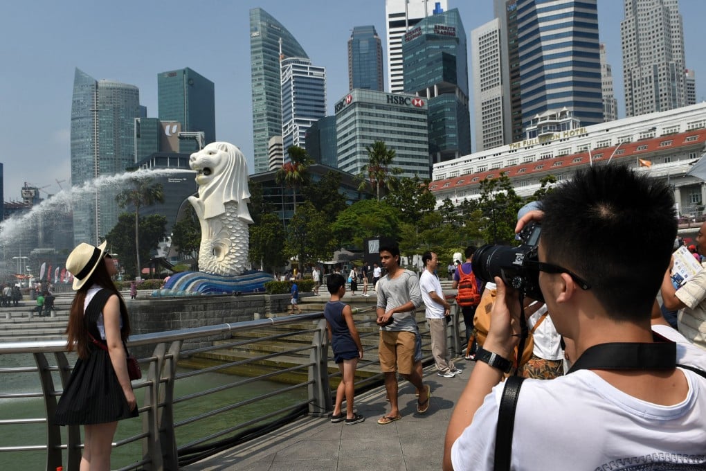 Chinese tourists take pictures against the iconic Merlion statue in Singapore. Phot: AFP