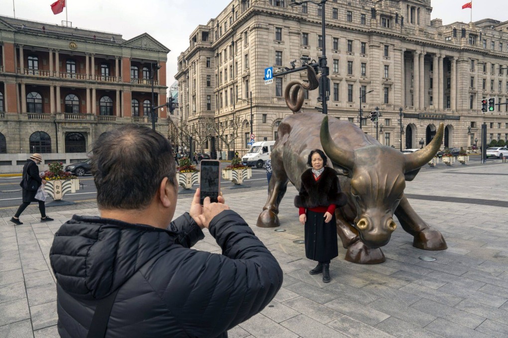 A tourist poses for photographs with the Bund Bull in Shanghai on February 19. Photo: Bloomberg