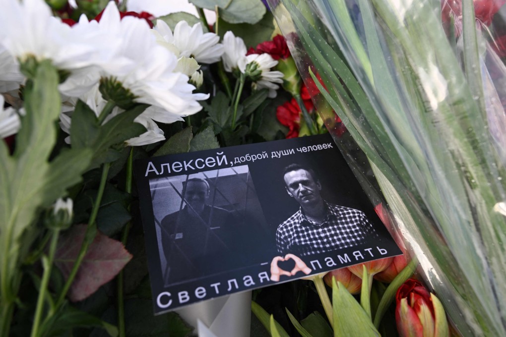A card with images of late Russian opposition leader Alexei Navalny is seen among flowers left at the Solovetsky Stone, a monument to political repression that has become one of the sites of tributes for Navalny, in Moscow. Photo: AFP