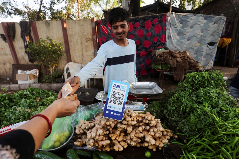 A customer pays cash to buy vegetables next to a QR code of Paytm, a digital payments firm, in Ahmedabad. Analysts anticipate more challenges in India’s tech sector in the coming months. Photo: Reuters