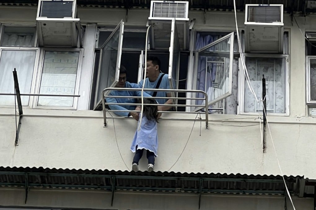 Two men attempt to free the girl from the ledge. She suffered no obvious injuries but was taken to Caritas Medical Centre for examination. Photo: Handout