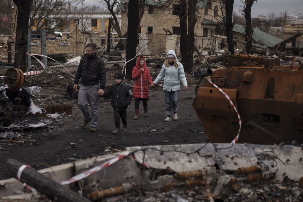 A family walks amid destroyed Russian tanks in Bucha, on the outskirts of Kyiv, Ukraine on April 6, 2022. On the two-year anniversary of Russia’s brutal invasion, there is a growing sense of uncertainty over how and when it will all end. Photo: AP