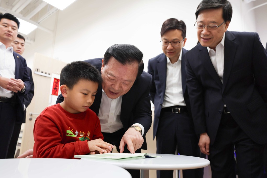 Top Beijing official Xia Baolong, with city leader John Lee Ka-chiu on the right, meets a boy at the first government-led “community living room” on Sunday. Photo: SCMP