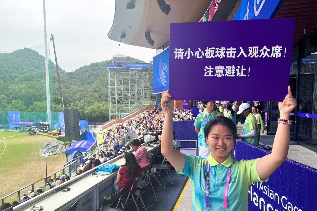 An Asian Games volunteer holds a sign warning spectators to beware of cricket balls being hit into the terraces during the quarter-final between India and Nepal in Hangzhou. Photo: Reuters