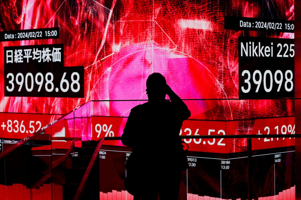 A visitor takes photos of an electronic screen displaying Japan’s Nikkei share average, which surged past an all-time record high set in December 1989, inside a building in Tokyo on February 22. Photo: Reuters