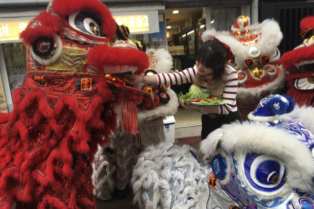 Ty Cake shop owner Shuying Gao feeds a lai see envelope to a lion heralding the Year of the Dragon in Belleville, Paris, France, in February 2024. The bustling Belleville Chinatown has long been a multilingual, cosmopolitan melting pot Photo: John Brunton