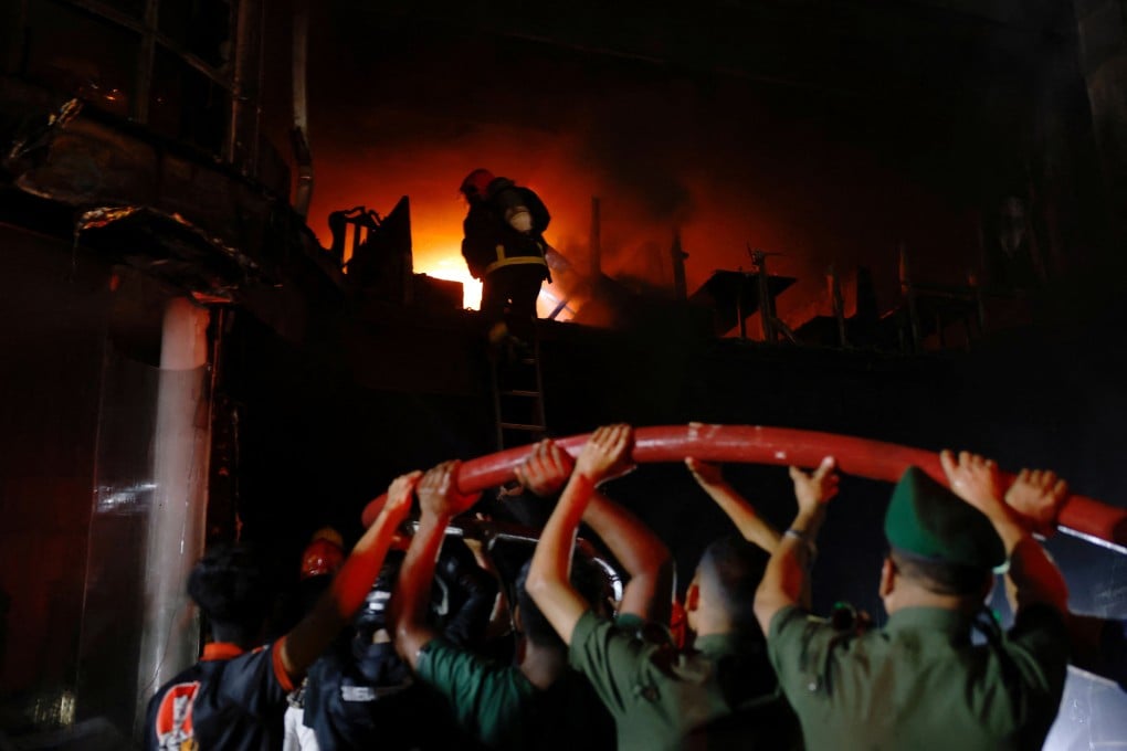 Volunteers carry a water pipe as firefighters spray water to douse the fire after a fire that broke out in a multi-storey building in Dhaka, Bangladesh, February 29, 2024. Photo: Reuters