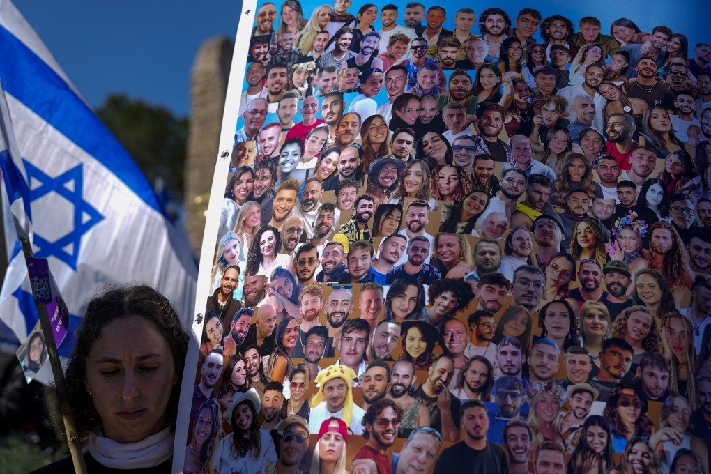 A woman holds a flag and a poster with pictures of revelers killed on October 7 at the Nova music festival by Hamas militants. File photo: AP
