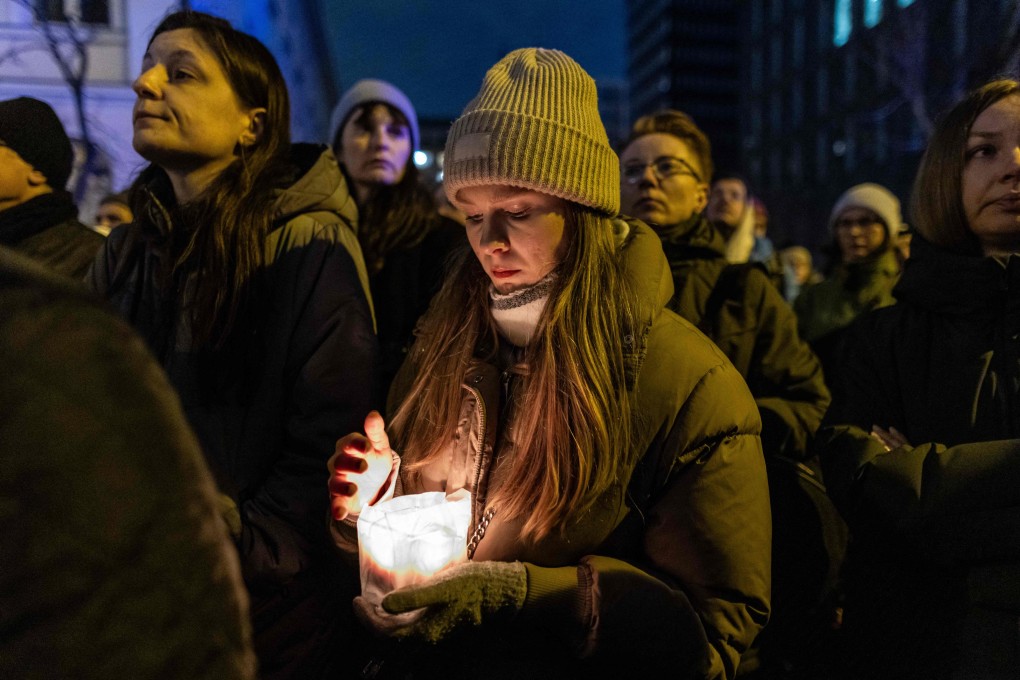 A woman holds a candle as she attends a vigil on Wednesday for Liza, a 25 year-old refugee from Belarus who died after being attacked, raped and severely beaten in downtown Warsaw. Photo: AFP