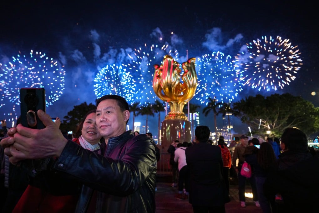 Visitors take a photograph, with a fireworks display to celebrate the Lunar New Year in the background, at Golden Bauhinia Squre in Wan Chai on February 11. Photo: Eugene Lee