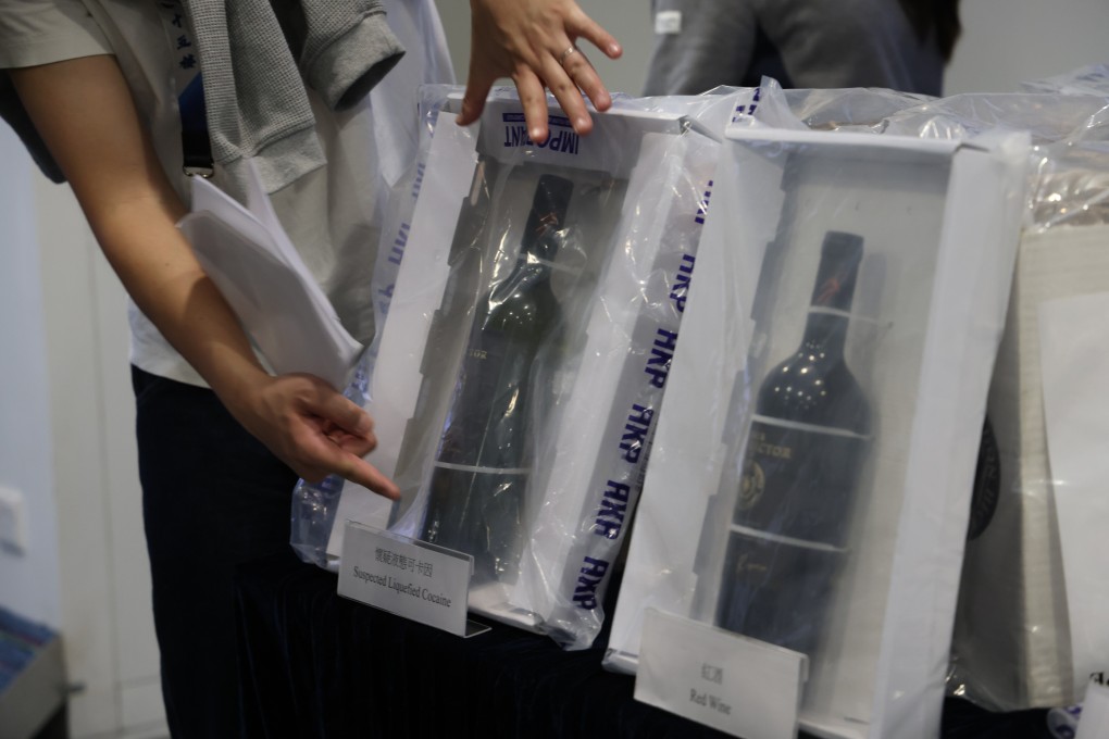 Officers show wine bottles allegedly to used conceal the liquid cocaine. Police also seized a 1kg slab of what appeared to be cocaine, 400 grams of suspected ketamine and 740 grams of cannabis buds. Photo: Jelly Tse