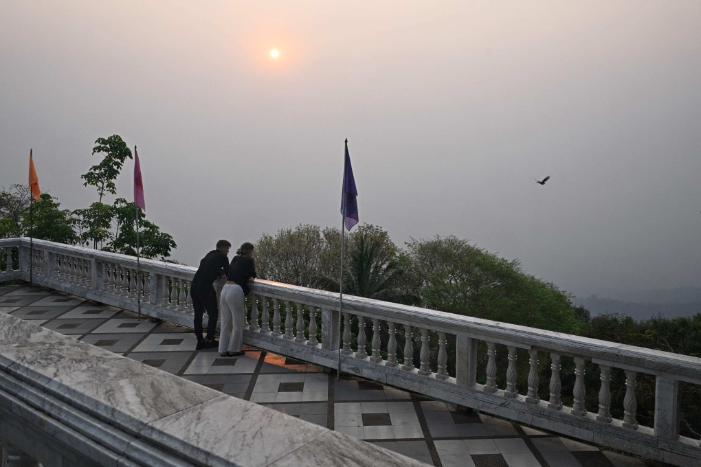 Tourists look out as high levels of air pollution obscure the view of Chiang Mai from atop Wat Phra That Doi Suthep temple on Friday. Photo: AFP