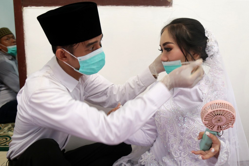 A groom puts a face mask on his bride before their wedding ceremony in Jakarta. Indonesia recorded only 1.79 million marriages in 2020. Photo: AFP