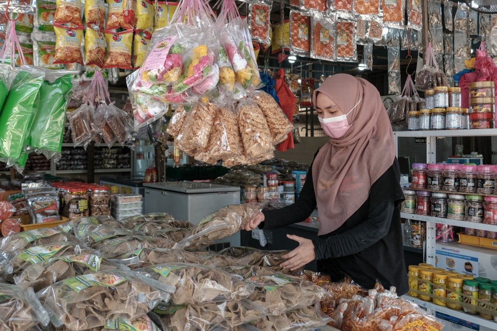 A worker arranges packaged fish crackers at a store in Terengganu. Ordinary Malaysians have been hit by the ringgit’s drop in value, as the cost of shopping surges with each depreciation. Photo: Bloomberg