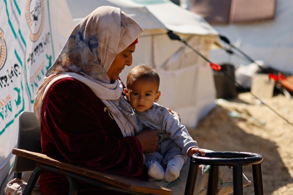 A woman holds a baby as displaced Palestinians, who fled their houses due to Israeli strikes take shelter in Rafah in the southern Gaza Strip, in February. Photo: Reuters