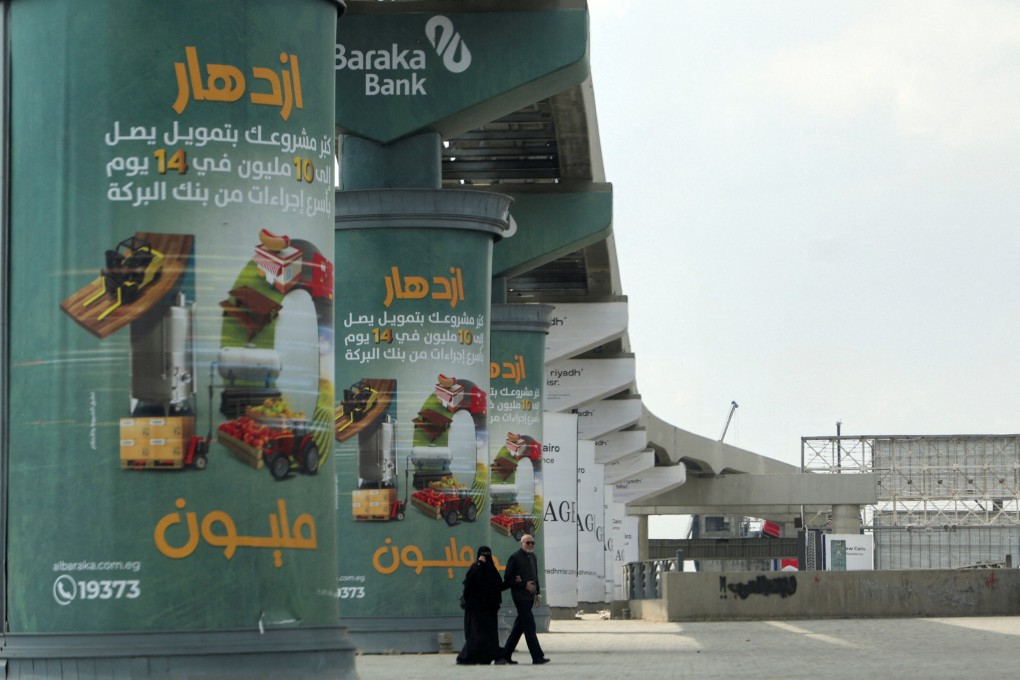 An Egyptian couple walks next to advertising credit investment certificates by a branch of Al Baraka Bank on walls of a new monorail line in Cairo, Egypt, on March 7. Photo: Reuters