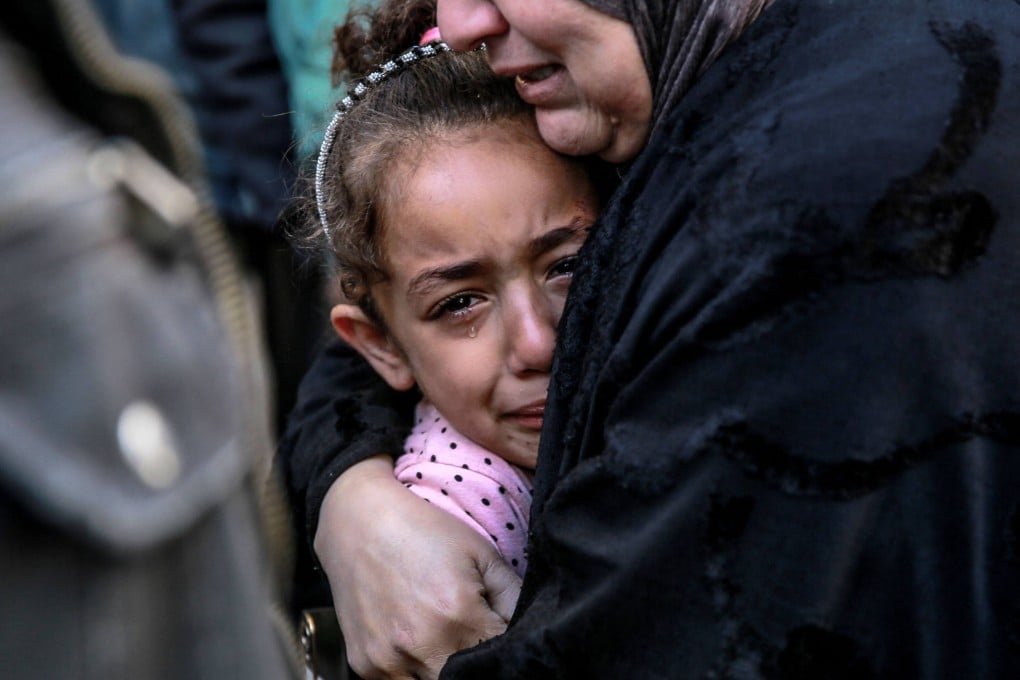 A Palestinian woman holds a child in front of the morgue at Al-Shifa hospital in Gaza City on Friday. Photo: AFP