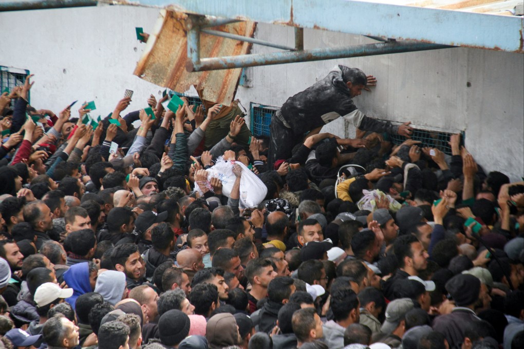 Palestinians gather to receive aid outside a UNRWA warehouse as Gazans face crisis levels of hunger. Photo: Reuters