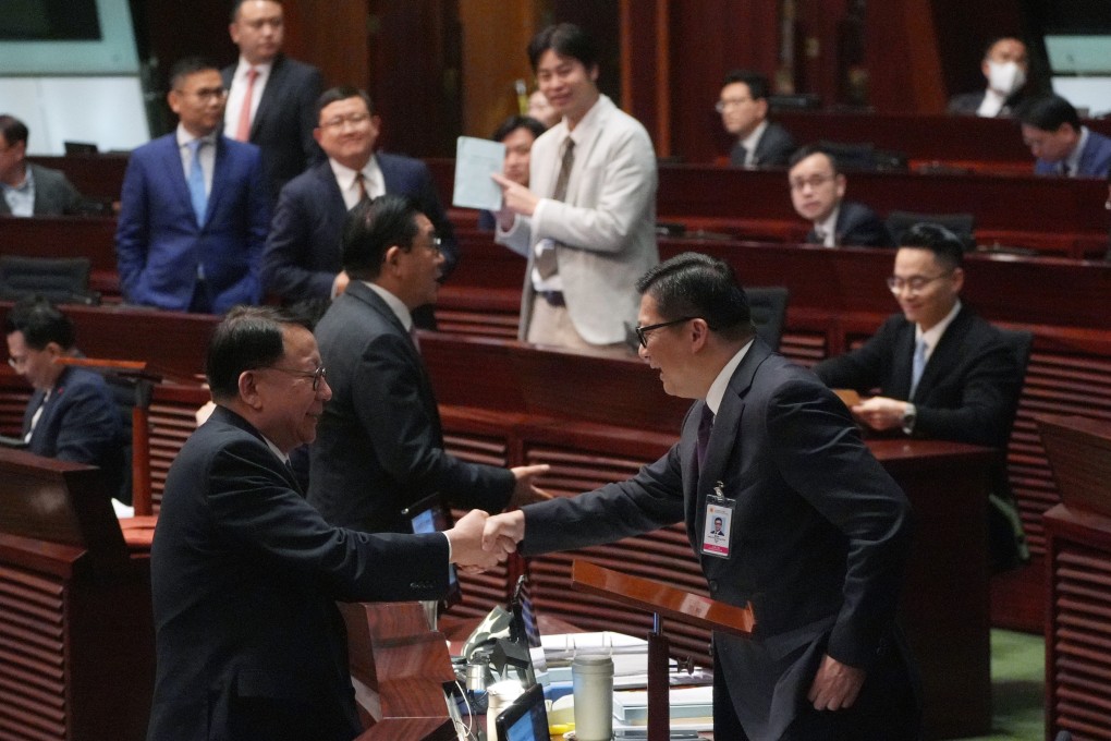 Chief Secretary for Administration Eric Chan Kwok-ki (L) shakes hand with Secretary for Justice Chris Tang Ping-kwung after  Basic Law Article 23 legislation at Legislative Council is passed. Photo: Eugene Lee