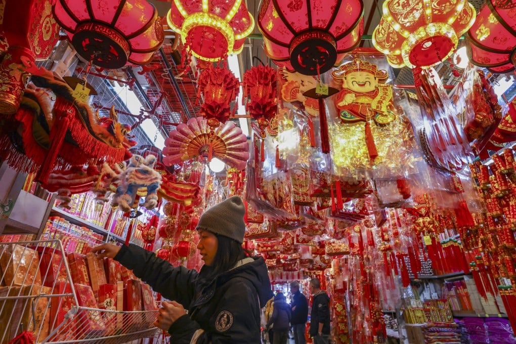 A shopper selects lai see - the red packets traditionally given out over the Lunar New Year holiday - amid a sea of festive ornaments at Tai Kiu Market in Yuen Long on January 28. Photo: Dickson Lee